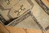 Folded vintage Oushak rug corner reveals geometric pattern and hand-knotted reverse.