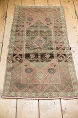 Distressed Oushak rug end, showing blush rose and olive green border with ivory fringe.