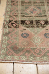 Corner close-up of Oushak runner with abrashed blush field, meandering olive border, and wear.