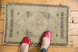 Vintage Oushak rug corner with charcoal vine border, faded ivory, and geometric medallion detail.