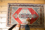 Hand knotted Oushak rug corner, showing cherry red field and geometric bud and vine main border.