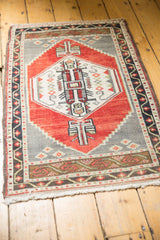 Fringed lower corner of Vintage Oushak rug, showing red and charcoal vine patterns.