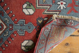 Folded vintage Oushak rug showing brick red pile, hand knotted reverse, and ivory fringe.