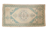 Distressed vintage Oushak rug featuring ivory field, seafoam green geometric medallion, and border, 2' x 3'8