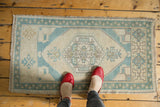 Ivory, mint, and pale bronze medallion pattern with distressed texture on vintage Oushak rug.