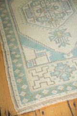 Distressed texture of vintage Oushak rug corner with ivory field and mint border.