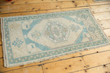 Distressed Oushak rug corner with mint seafoam border, geometric motifs, and even pile wear.