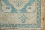 Distressed Oushak rug corner: mint seafoam green-blue vine and bud border with fringe.