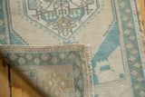 Vintage distressed Oushak rug corner showing even pile wear and intact selvage.