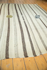 Vintage Turkish Kilim with natural striped undyed wool, worn texture, and a mended patch.