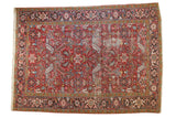 Vintage Persian Heriz carpet: brick red, navy geometric floral with low pile, exposed foundation.