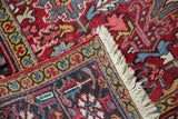 Vintage Heriz carpet corner detail, showing hand-knotted construction, fringe, and geometric borders.