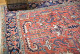 Vintage Heriz rug's brick red field, displaying rectilinear floral motifs, low pile, and faint foundation.
