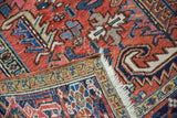 Heriz carpet's low pile with brick red, navy, ivory geometric floral motifs and fringe.