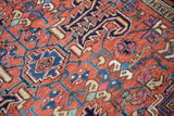 Low pile on vintage Heriz rug with rectilinear floral motifs in brick red, navy, blush.