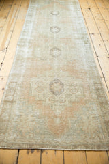 Distressed Oushak rug texture with geometric stepped medallions in peach and ivory.