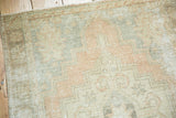 Distressed vintage Oushak runner corner, geometric stepped pattern in pale apricot and slate blue tones.
