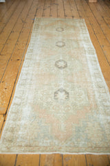 Distressed texture, geometric medallions in pale peach, ivory, and soft blue with fringe.