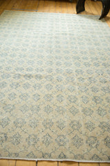 Distressed Oushak rug pile revealing faded navy floral lattice on soft ivory.