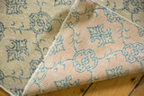 Distressed Oushak carpet's antique ivory pile, navy vinery, and pink hand-knotted foundation.