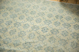 Distressed Oushak rug with mostly even wear, faint foundation, and faded navy floral vinery.