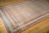 Distressed vintage Mir Serbend carpet corner with worn madder root red field and pale borders.