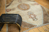 Potted blossom motif and detailed stepped borders on a vintage Oushak rug in rust, blue, and sand.