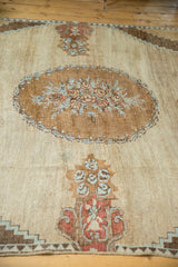Oushak carpet detail: floral roundel, potted plant motifs, coffee brown, rust, powder blue.