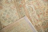 Folded corner of distressed Sparta carpet, showing worn pile and visible foundation in ivory, rose, blue.