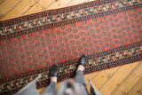 The allover boteh design in staggered rows on a madder red vintage Persian runner.