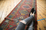 A vintage Karaja runner's repeating column of latch-hook diamond medallions in red, blue, and gold.