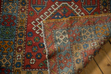 A folded corner of the vintage Karaja runner reveals its hand-knotted construction and intact edge.