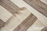 Handwoven texture of brown and ivory striped vintage Moroccan Kilim runner, with folded corner.