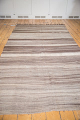 Horizontal striations and abrashes in natural brown, coffee, and ivory on a Moroccan Kilim.