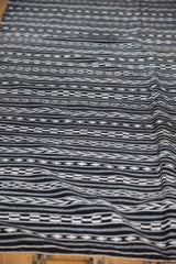 Geometric horizontal bands with woven checker and arrow motifs in black and ivory.