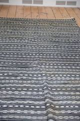 Texture of handwoven Moroccan Kilim with black, charcoal, ivory geometric arrow and checker patterns.