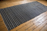 Geometric arrow and checker motifs woven into black, charcoal, and ivory horizontal bands.
