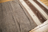 Moroccan Kilim runner featuring striated brown bands and ivory geometric figures.