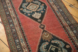 Madder red field, navy serrated medallion, intricate border, showing even pile wear.