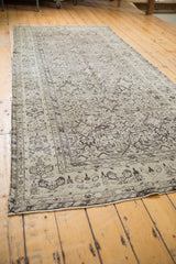 Angled view of a vintage Hamadan runner showing its neutral-toned, repeating Herati pattern.