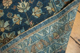 Folded vintage Lilihan runner edge, revealing navy floral field and light blue woven foundation.