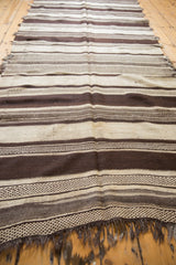 Hand-woven Moroccan Kilim runner showcasing natural ivory and chocolate brown stripes with intricate patterns and fringe.