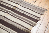 Natural ivory and chocolate brown striped bands on a handwoven Moroccan Kilim rug.