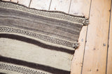 Textured fringe and patterned natural ivory and chocolate brown stripes at rug end.