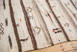 Mixed-weave vintage Moroccan Kilim close-up, showing ivory and brown stripes with textural pile and pictorial elements.