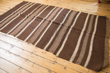 Textured geometric pattern within brown and ivory bands of a vintage Moroccan Kilim, with secured edge.