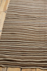 Striated, striped texture of a hand woven Moroccan Kilim rug in natural browns and beige.