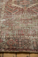 Distressed Karaja rug's geometric pattern in muted brick red, seafoam green, and exposed foundation.