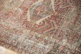 Textural detail of a distressed Karaja rug, geometric motifs, dusty brick red, and light foundation.