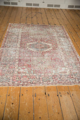 Distressed Karaja rug end with secured fringe and worn geometric motifs in red, green, charcoal.